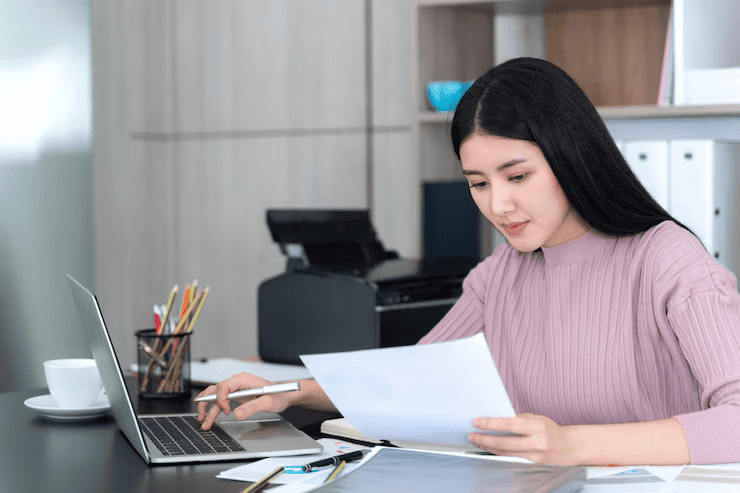 Focused on regulatory compliance, a woman compiles reports and verifies information to meet nonexistent entities BOI filing requirements.