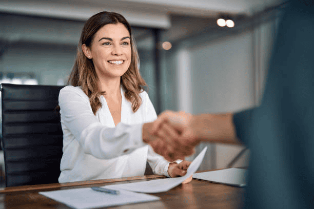 A smiling woman shaking hands with a client highlighting professional service firms.