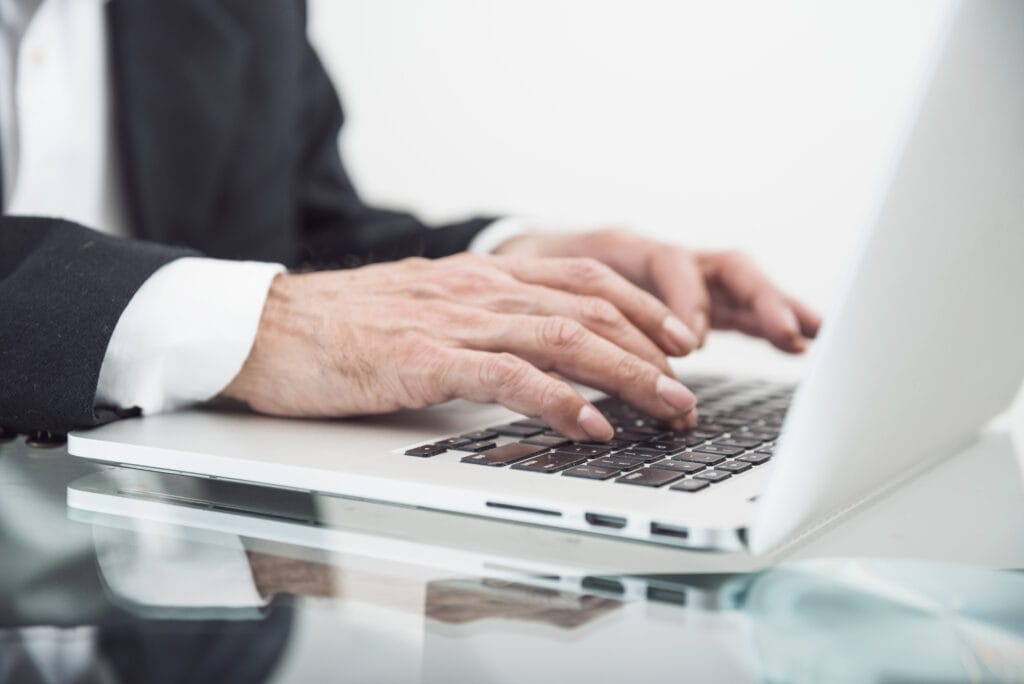 Hand of a typing man signifying how does a registered agent work.
